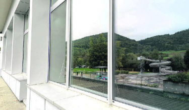 In den Fenstern des Hallenbades spiegelt sich das Fricker Freibad. Foto: Simone Rufli
